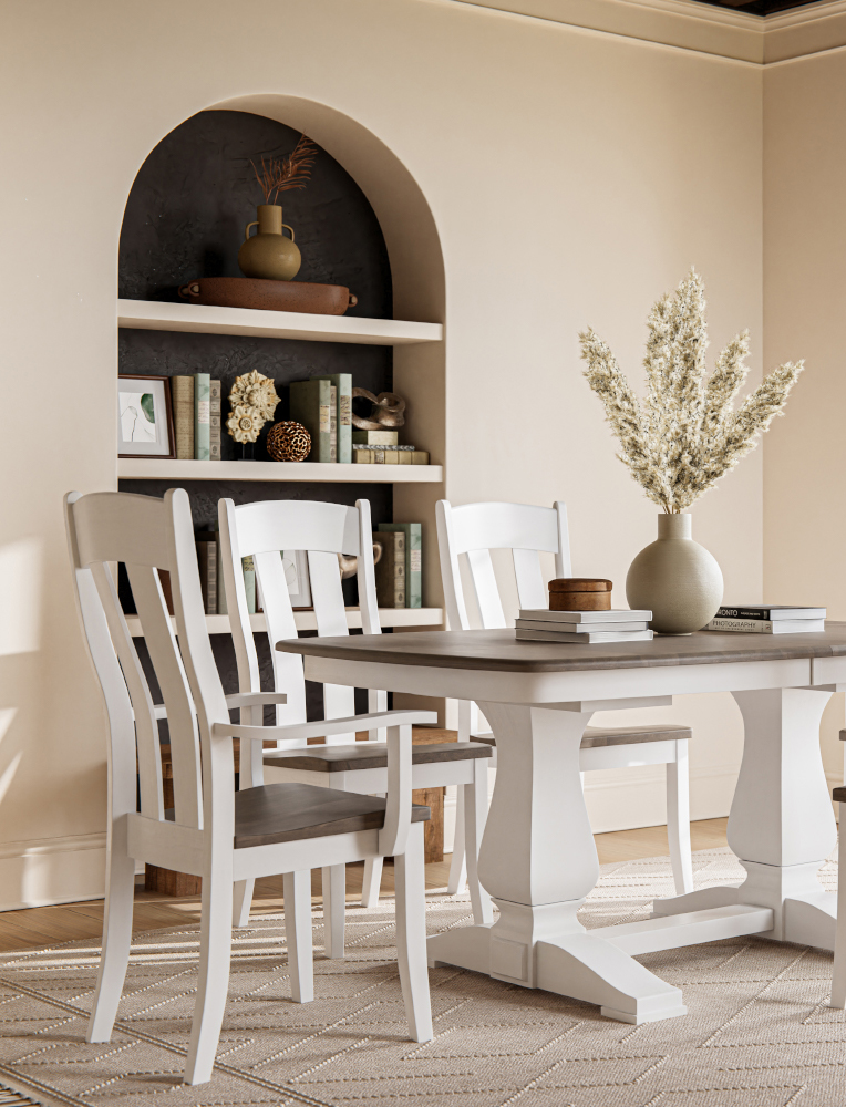 A two-tone Amish dining set featuring a white double-pedestal table and matching chairs with a natural wood seat and tabletop, set in a cozy, minimalist room with a built-in arched bookshelf. This elegant furniture reflects the fine craftsmanship available at Amish stores in Hamptonville, NC.