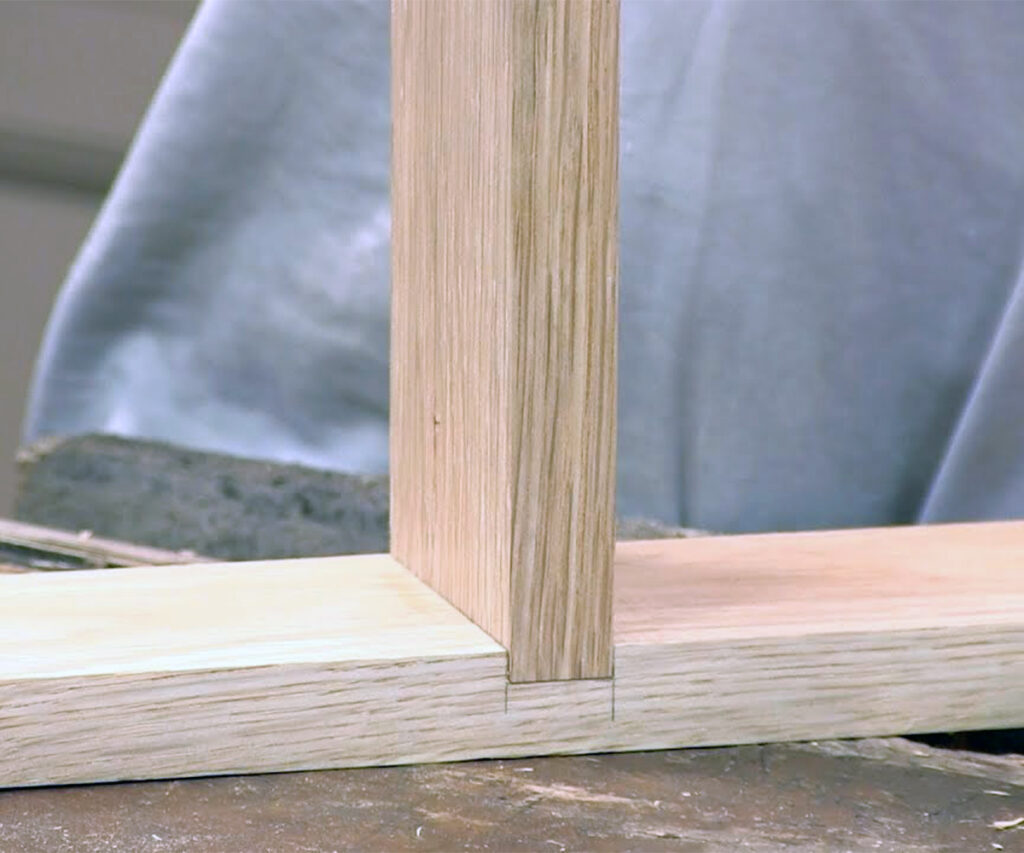 Close-up of dado joint fitting a vertical wood panel into a horizontal board