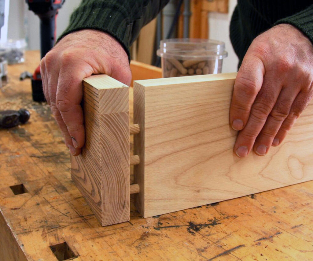 Close-up of dowel joints connecting two hardwood pieces during furniture assembly