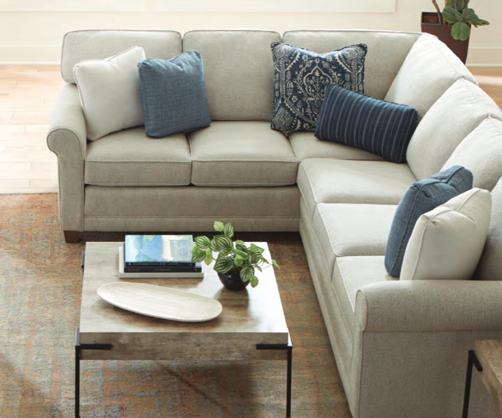 Light sectional sofa with blue accent pillows and coffee table in cozy living room.