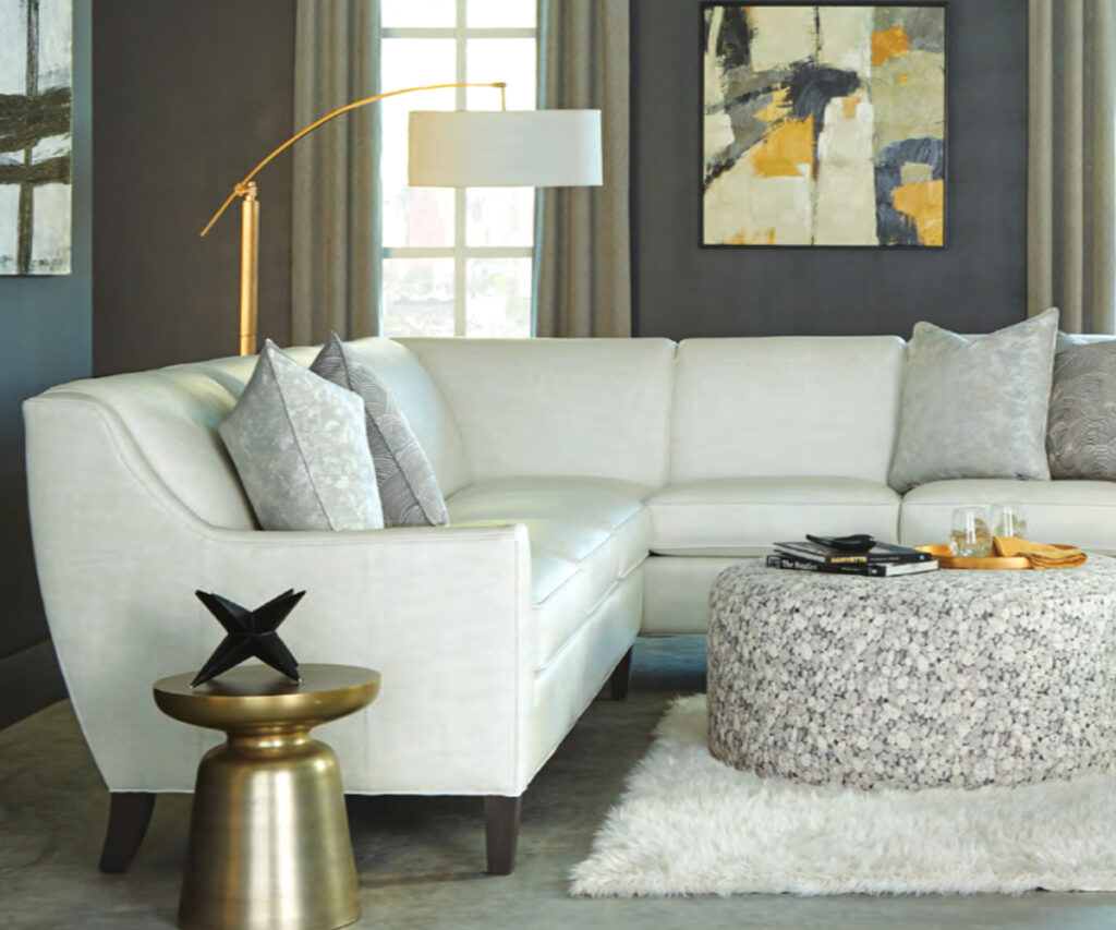 Modern light sectional sofa with accent pillows, ottoman table, and floor lamp.